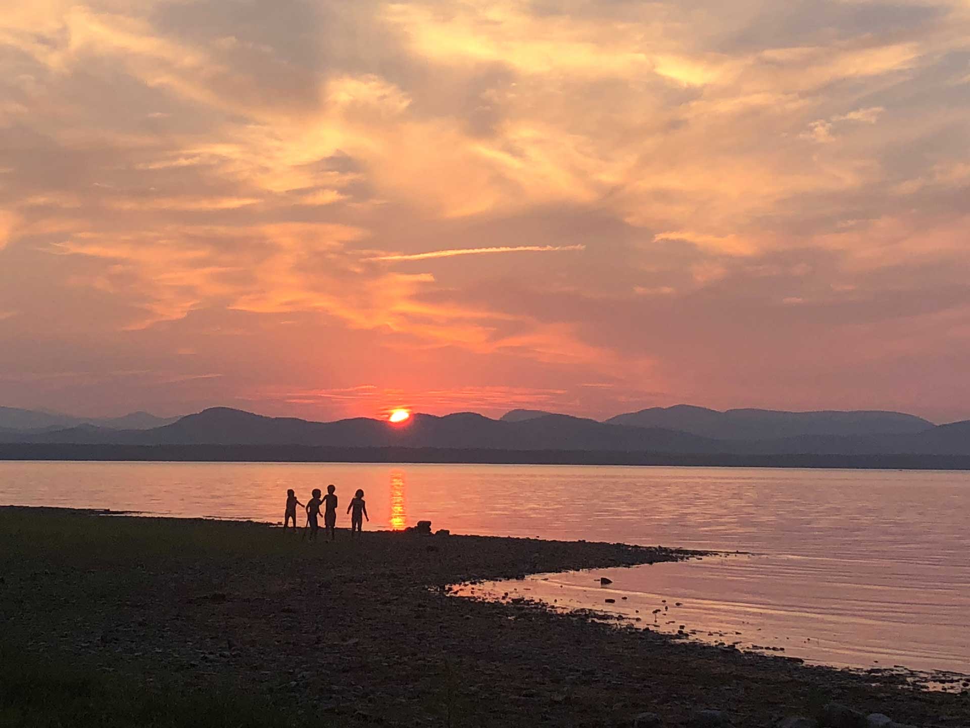 Children playing on the beach at sunset in Charlotte, VT